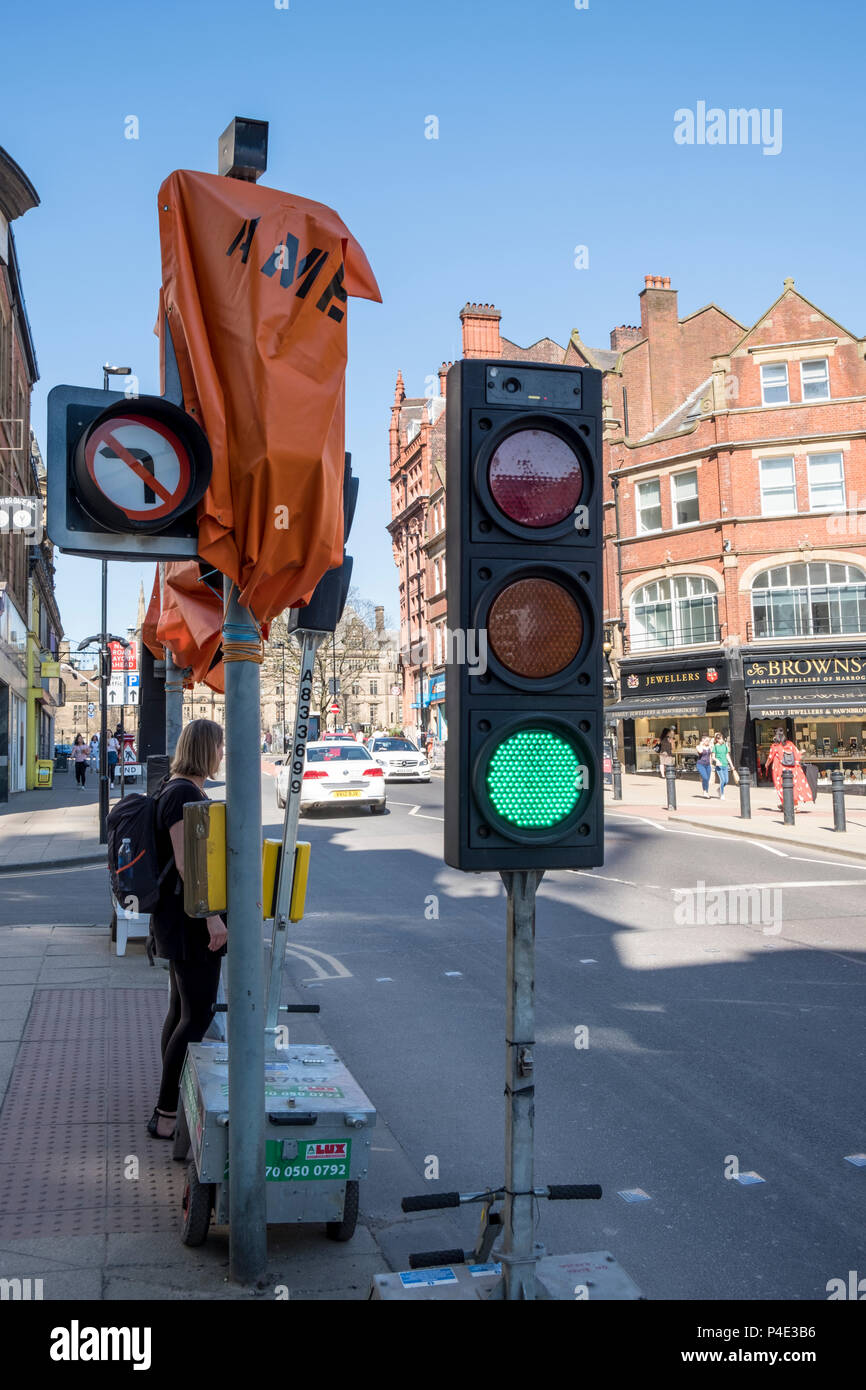 Persona in attesa di attraversare la strada a traffico temporaneo segnali, Sheffield, England, Regno Unito Foto Stock