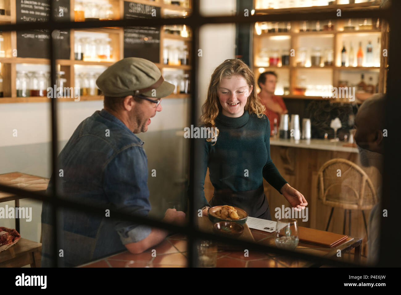 Sorridente cameriera che serve cibo di un bistro cliente Foto Stock