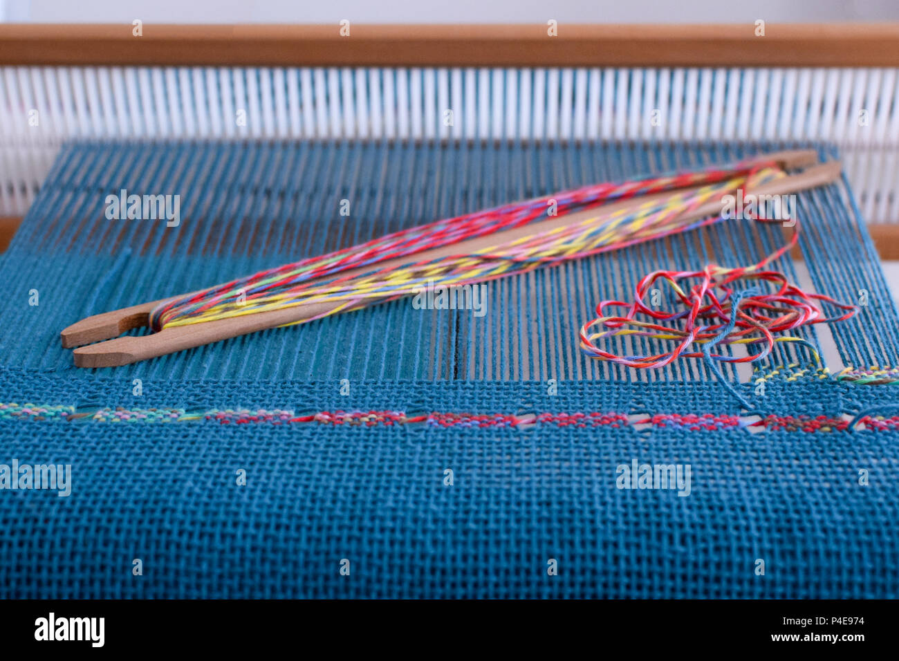 Pizzi spagnoli tessitura su liccio rigida del telaio blu con fili di ordito e di trama colorata Foto Stock