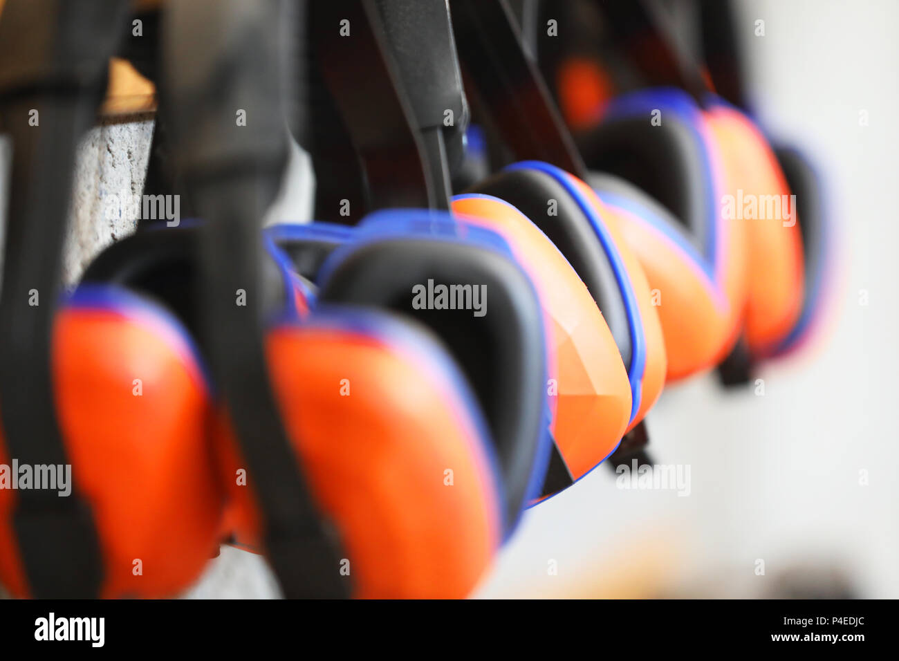 Fila di orange cuffie di protezione per le orecchie su un rack. Salute e sicurezza sul lavoro la sordità concetto. sicuro pratica di lavoro. Foto Stock