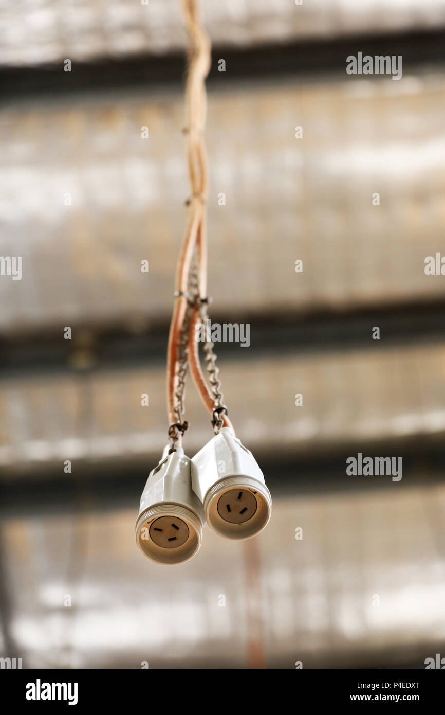 Una coppia della presa di alimentazione a 3 pin del cavo a filo del cavo appeso ad un soffitto di fabbrica del tetto. alimentazione. i cablaggi elettrici in un workshop. Foto Stock