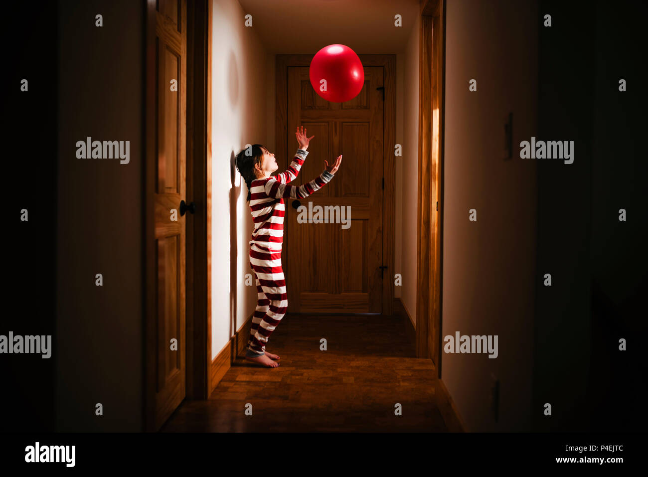 Ragazza in piedi in corridoio a giocare con una palla gigante Foto Stock
