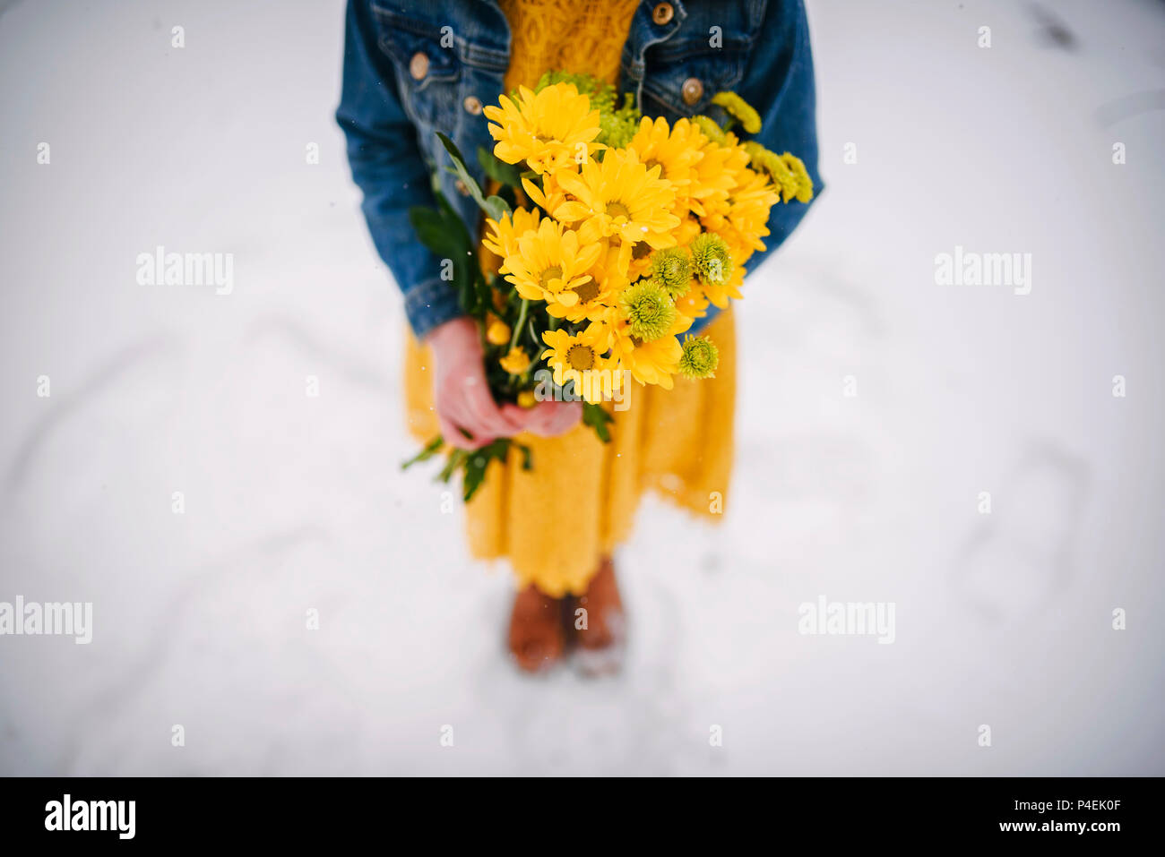 Ragazza in piedi nella neve tenendo un mazzo di fiori Foto Stock