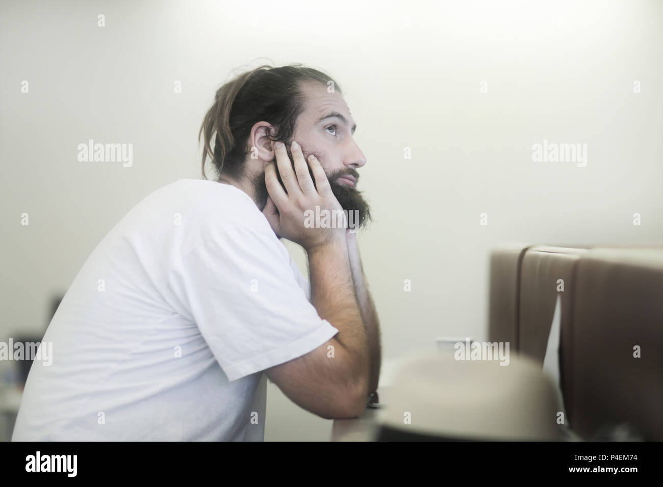 Uomo seduto a tavola fantasticando Foto Stock