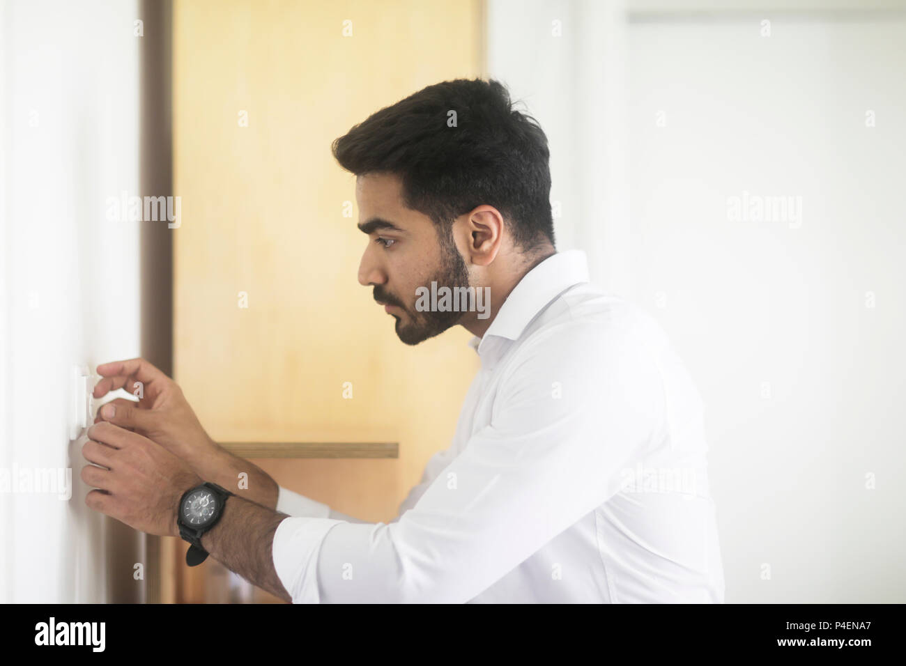 Uomo di regolazione di un pulsante di comando su una parete Foto Stock