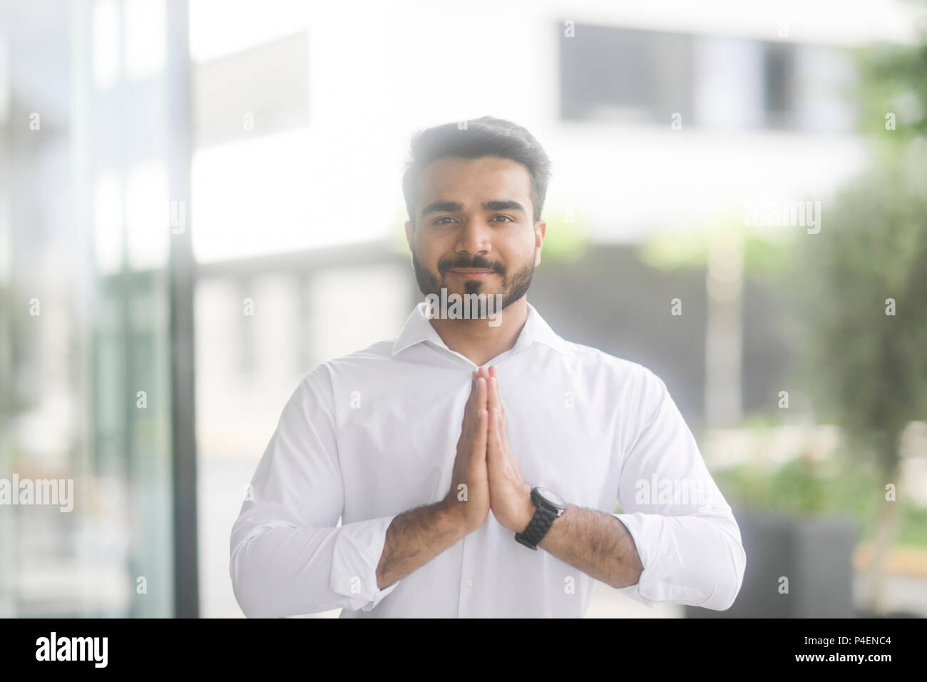 Imprenditore sorridente in piedi all'aperto fare yoga Foto Stock