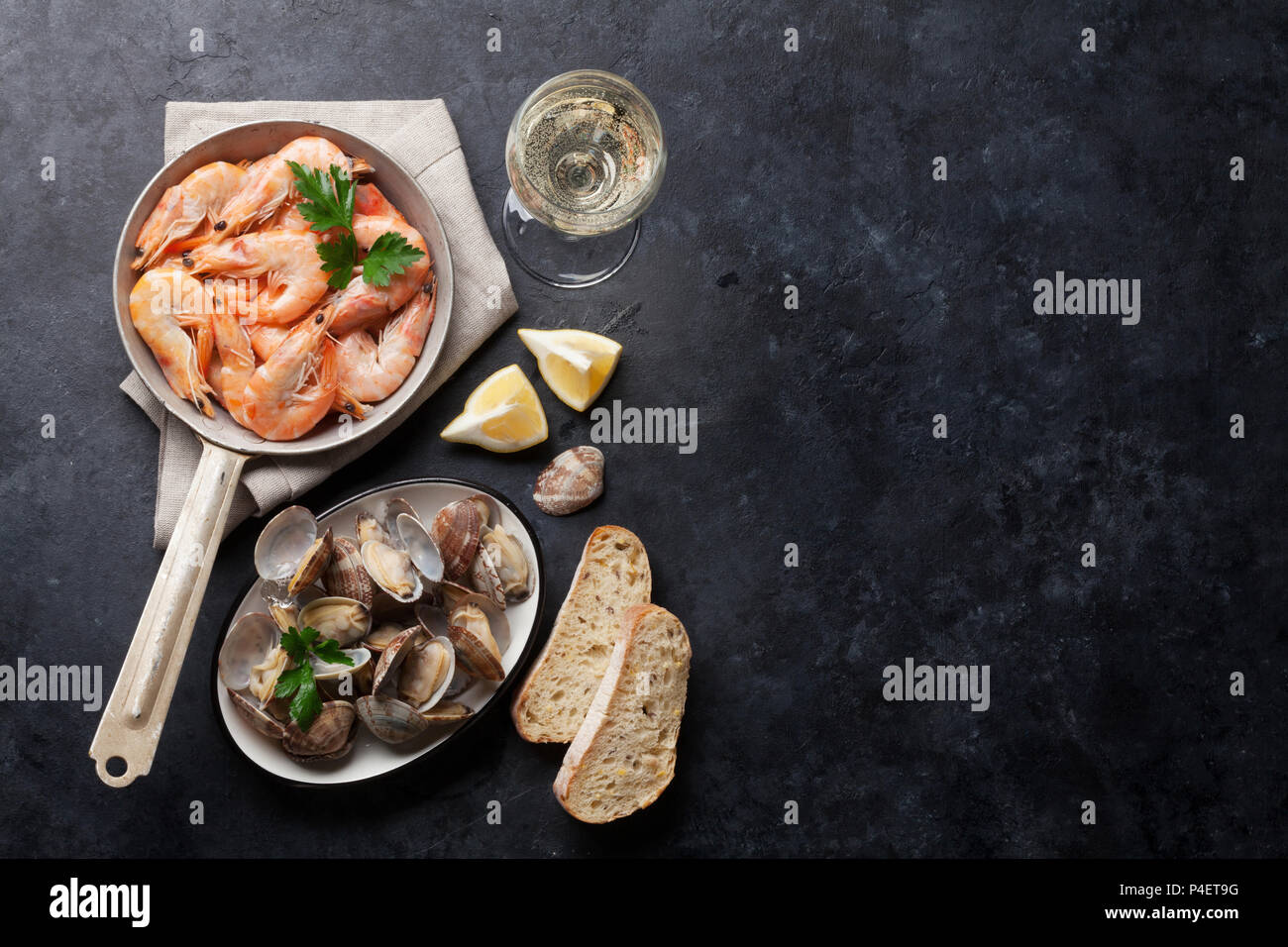 Piatti a base di pesce fresco e vino bianco sul tavolo di pietra. Cappesante e gamberetti. Vista da sopra con lo spazio di copia Foto Stock