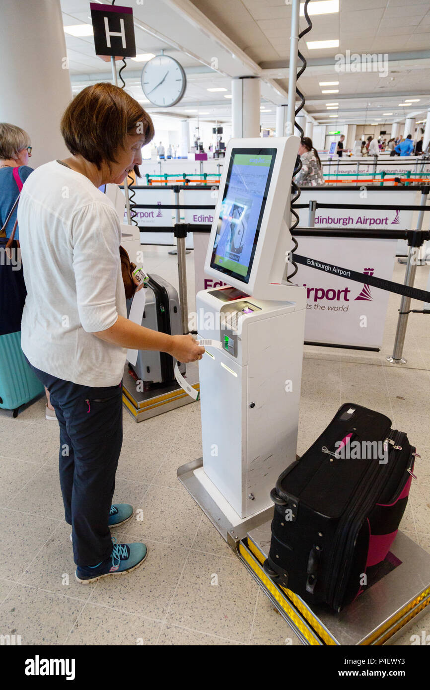 Una donna air passenger facendo self check-in del suo bagaglio a Edinburgh Airport Terminal, Edimburgo Scozia UK Foto Stock