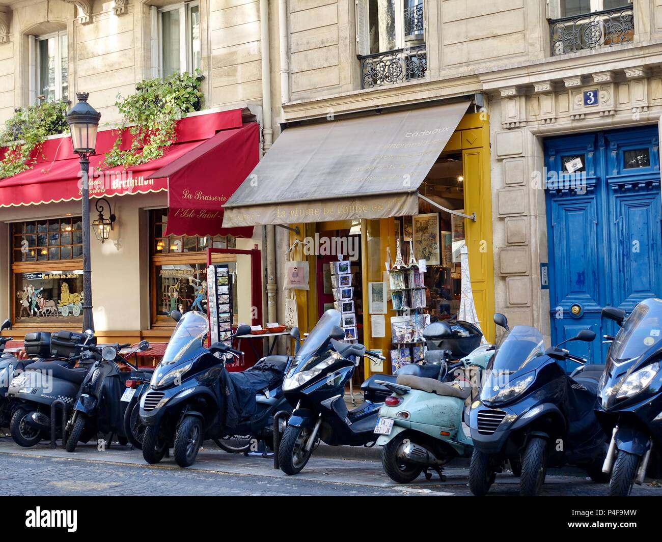 Moto parcheggiate al di fuori di negozi a île Saint-Louis su il giorno più lungo dell'anno, Parigi, Francia Foto Stock