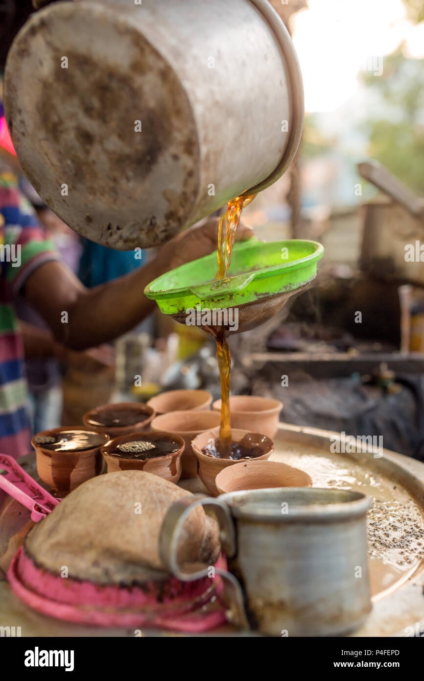 L'uomo versare la tazza di tè caldo stile indiano o chai per i clienti nel suo negozio lungo la strada in Kolkata, India Foto Stock