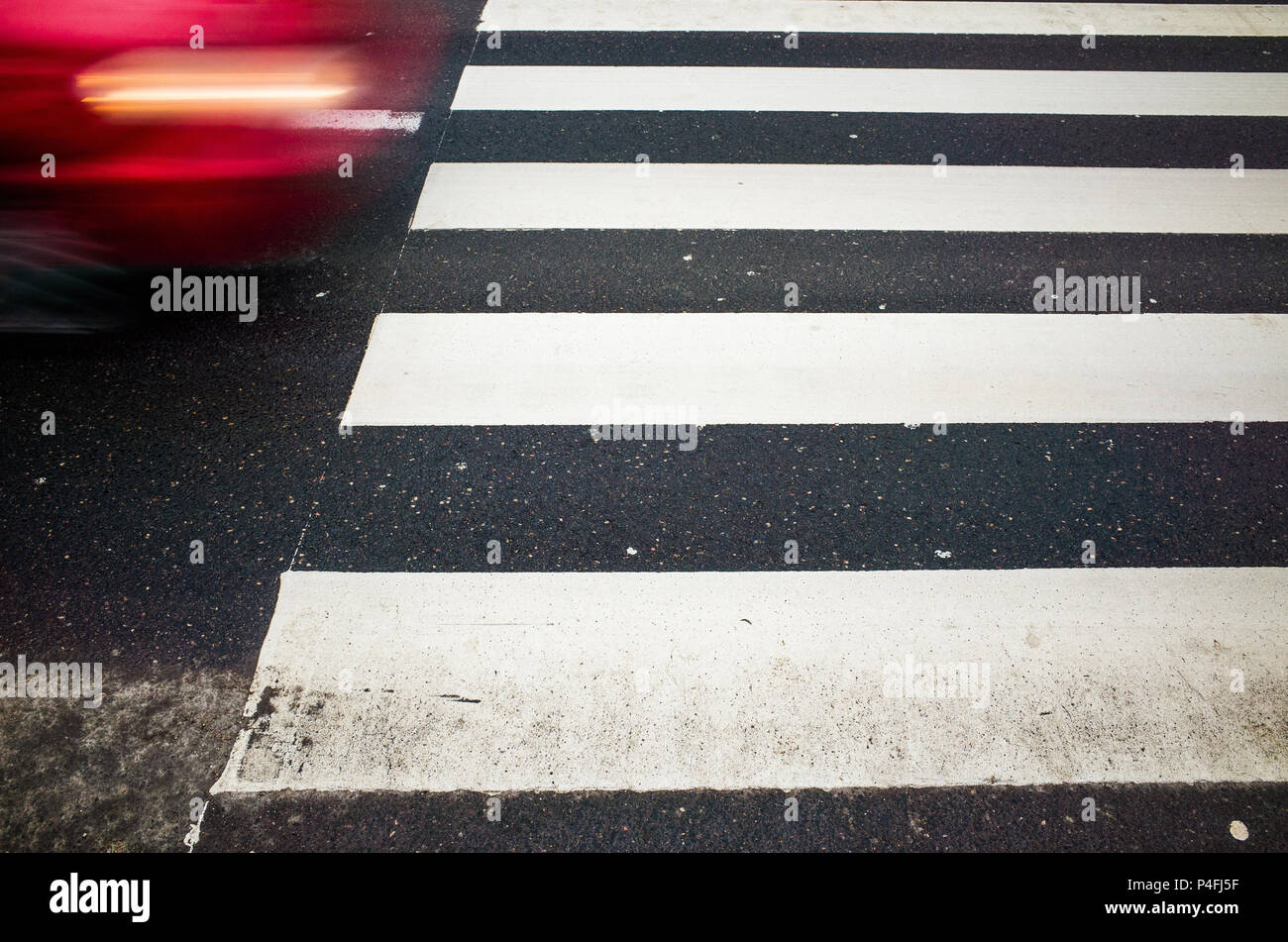Parte di auto rossa in movimento e dipinte di fresco attraversamento pedonale Foto Stock