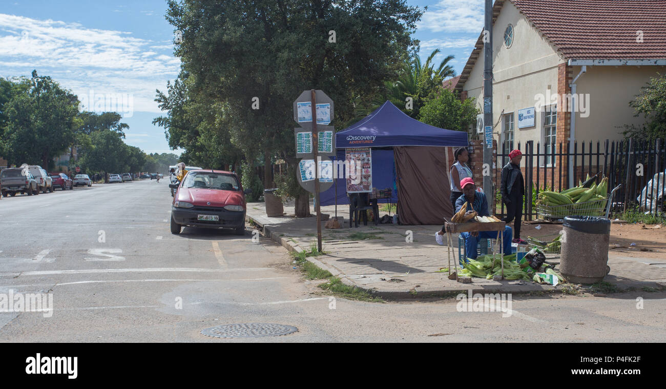 Venditore di strada africano che vende e cucinando il mais sulla pannocchia, mielies o mais sul marciapiede in una città rurale Mahikeng, Sudafrica concetto di vita quotidiana Foto Stock