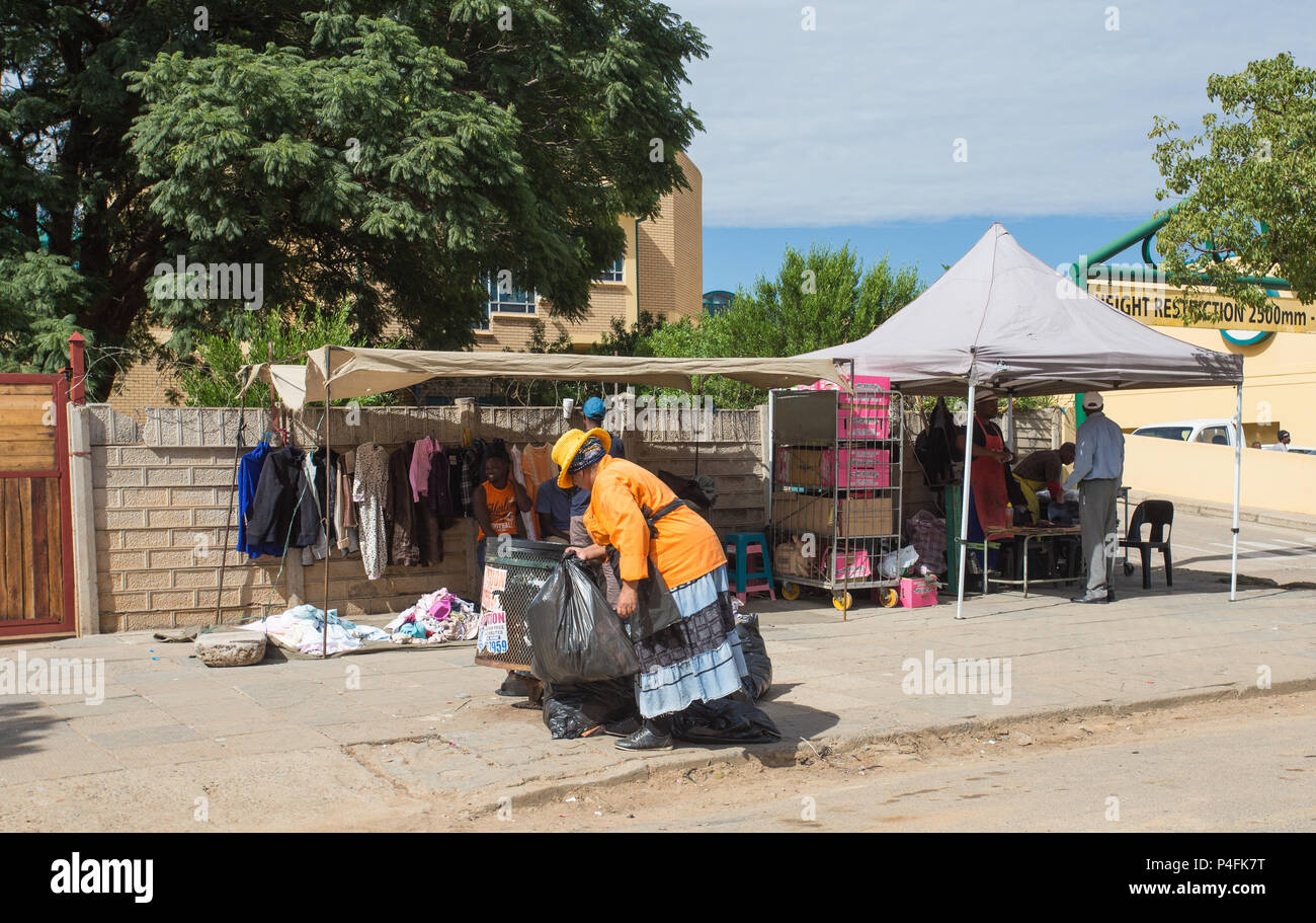 Garbage collector di fronte ai venditori ambulanti sul marciapiede a Mahikeng, Sud Africa concetto ambiente pulito e piccole imprese Foto Stock