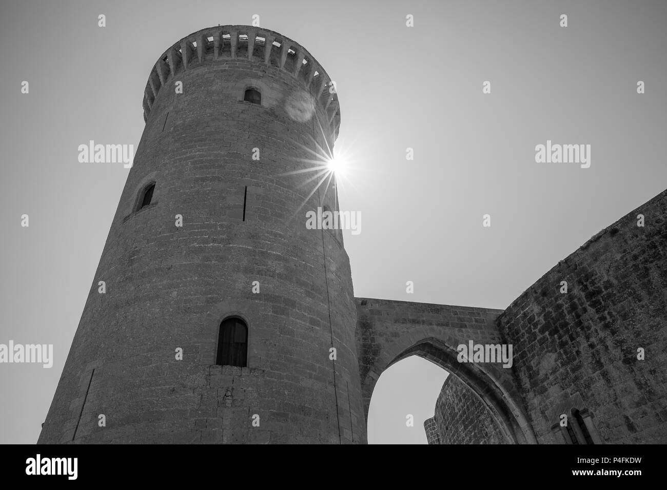Il vecchio castello fortificato alta sopra la Palma di Maiorca in bianco e nero con un naturale starburst sun in Spagna Foto Stock