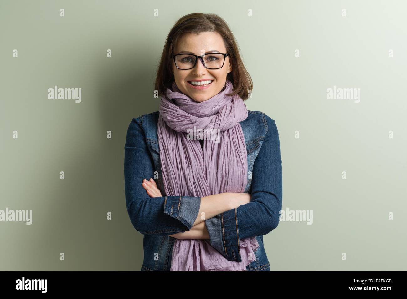 Ritratto di donna di mezza età con bracci incrociati. Sfondo muro verde Foto Stock