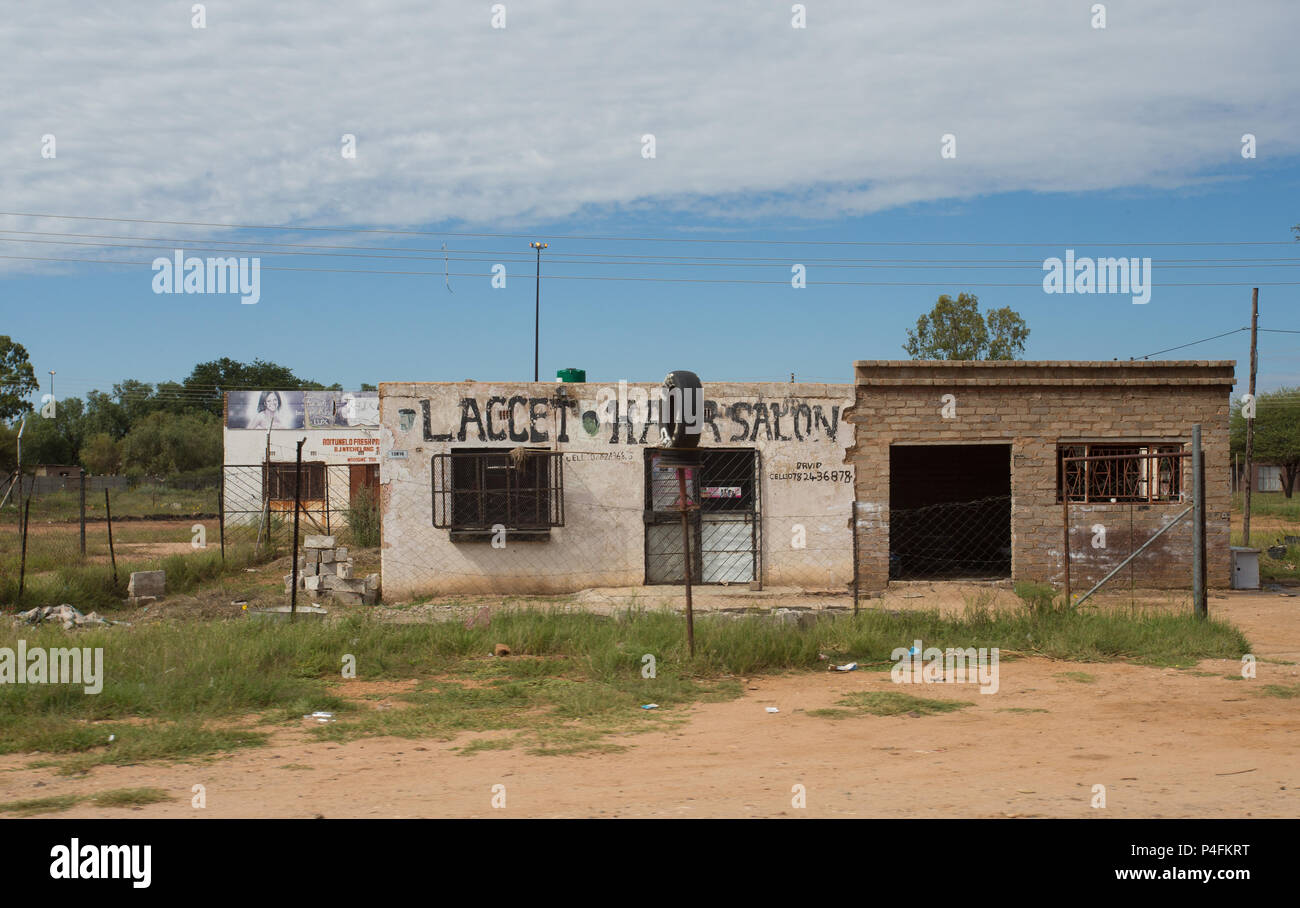 Parrucchiere africano rurale sul lato della strada in vecchio edificio in mattoni dilapidati in ambiente rurale della provincia nord-occidentale, Sudafrica Foto Stock