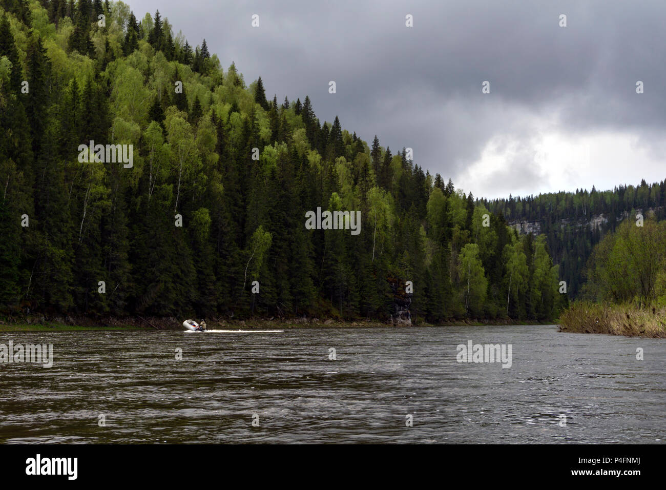 Paesaggio del fiume Ural Usva, il Chusovaya tributario, con pittoreschi boschiva costiera scogliere e una pesca barca gonfiabile in distanza, su un Foto Stock