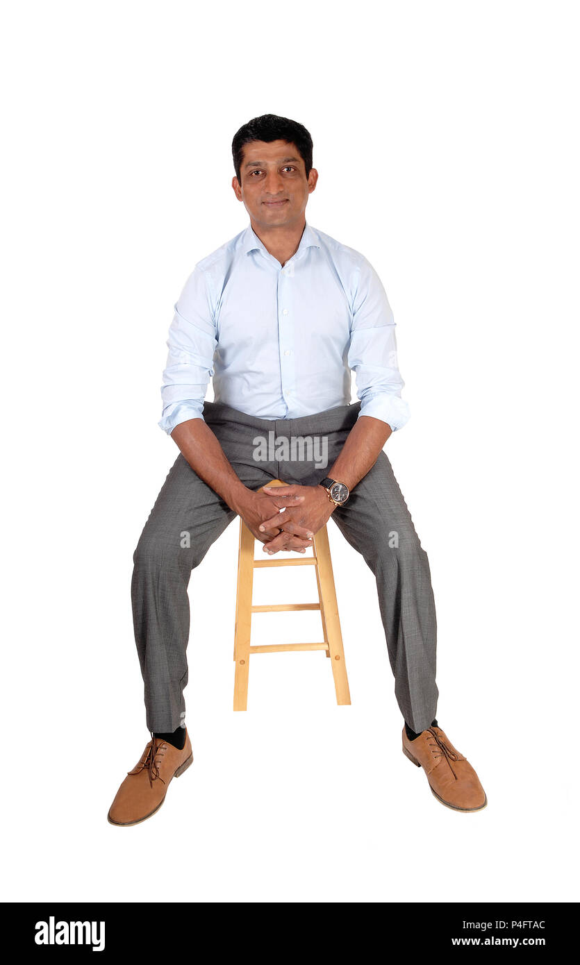 Una buona ricerca East Indian uomo in un abito pantalone e luce maglietta blu seduta su una poltrona, isolato per sfondo bianco Foto Stock