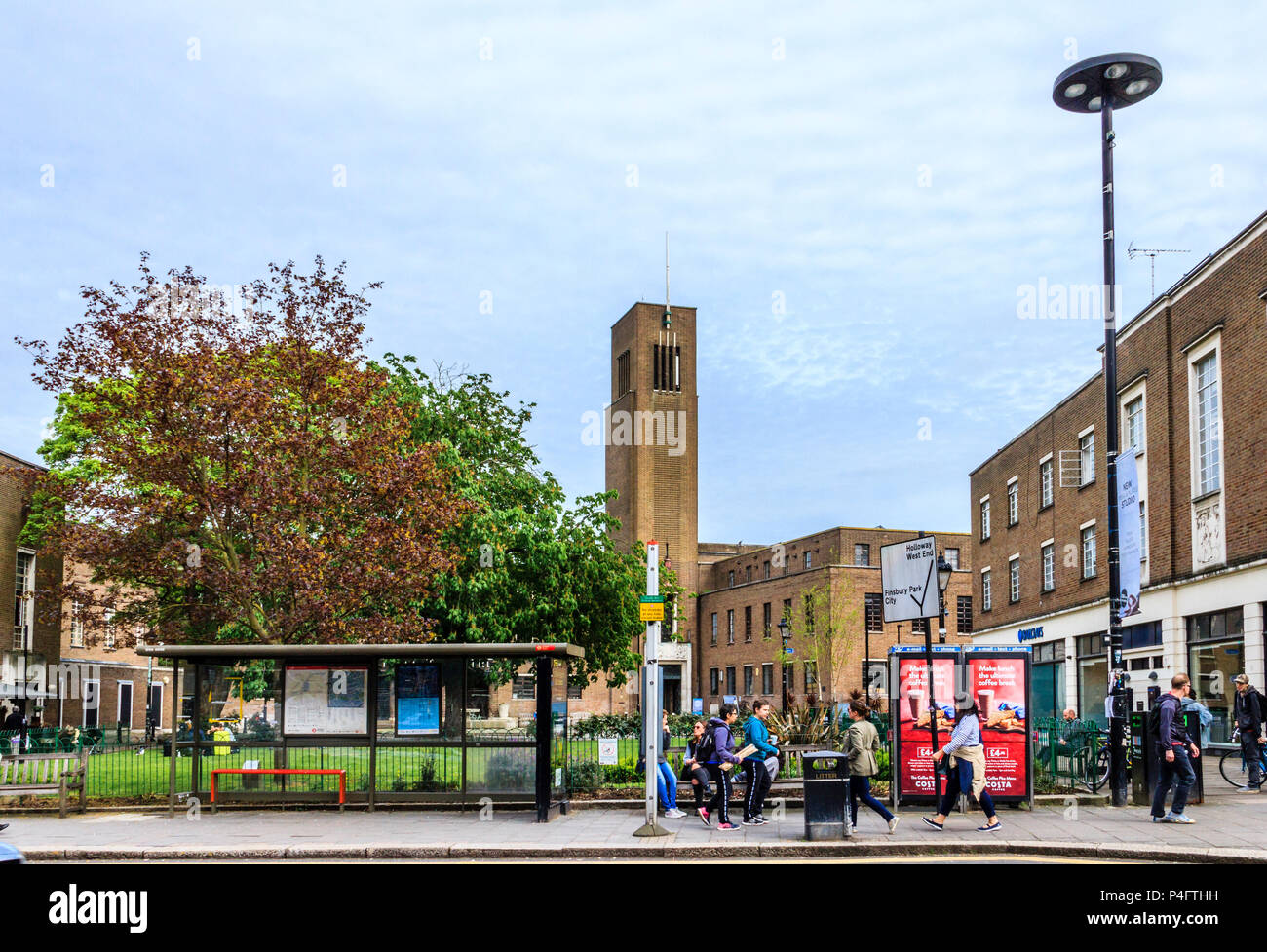 Persone in attesa ad una fermata degli autobus nel centro di Crouch End, sullo sfondo la art deco storico municipio, a nord di Londra, Regno Unito Foto Stock
