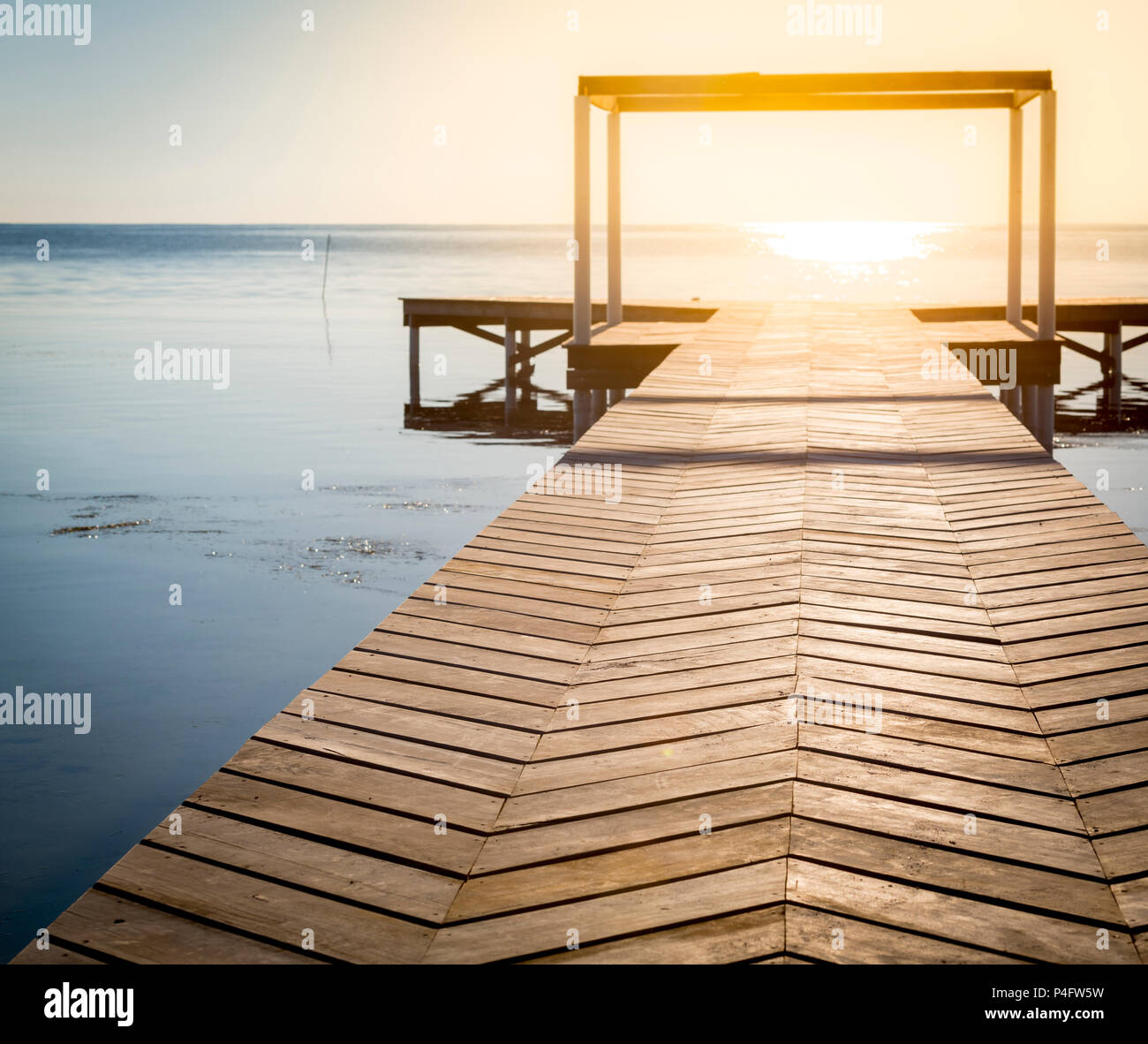 Sfondo spirituale di sunrise al termine di una passerella in legno su acque calme con spazio di copia Foto Stock
