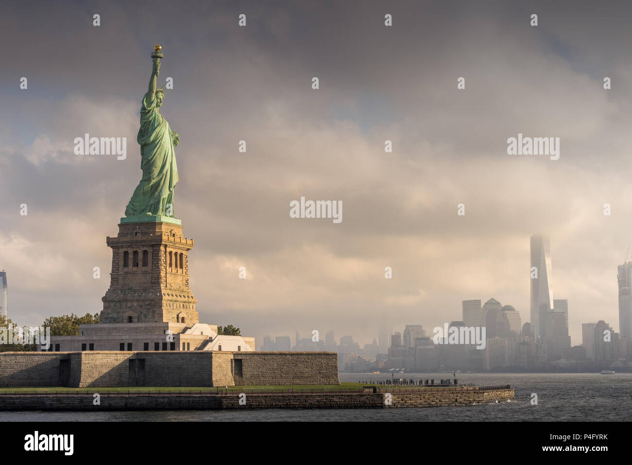 La Statua della Libertà guarda con orgoglio la nube coprì Manhattan, New York City. Foto Stock