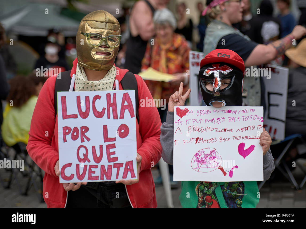 Portland, Oregon, Stati Uniti d'America. 21 Giugno, 2018. Una donna e suo figlio di usura di wrestling messicano maschere e tenere i segni al di fuori dell'ufficio nel campo degli Stati Uniti in materia di immigrazione e imposizione doganale (ghiaccio) a Portland, Oregon. L ufficio è stato bloccato dai manifestanti per diversi giorni prima di arrestare le operazioni su Giugno 20. I manifestanti sono opponendosi alla separazione delle famiglie detenuti mentre cercano asilo su STATI UNITI-Messico frontiera. Credito: Paul Jeffrey/Alamy Live News Foto Stock