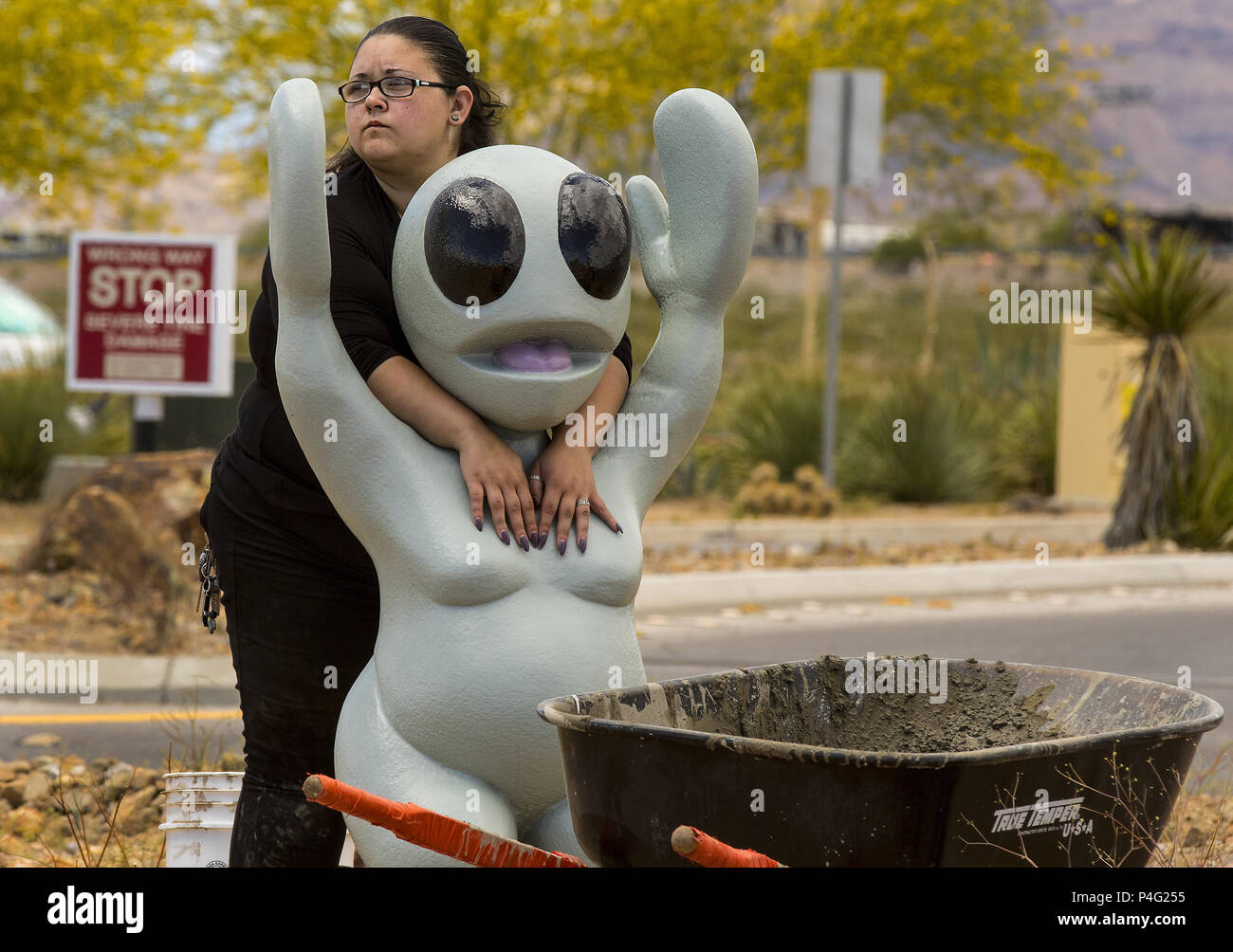 Las Vegas, Nevada, USA. 18 Maggio, 2017. Assistente artista Gia Ray mantiene un alieno in luogo come essi li di cemento per il completamento installazione artista Jesse Carson Smigel's Ã¢â'¬Å"Ti ho detto di non dipingere Hot OrangeÃ¢â'¬Â UFO scultura pezzo per l'arte centrato il progetto presso la contea di Clark complesso di ripresa. Credito: L.E. Baskow/ZUMA filo/Alamy Live News Foto Stock