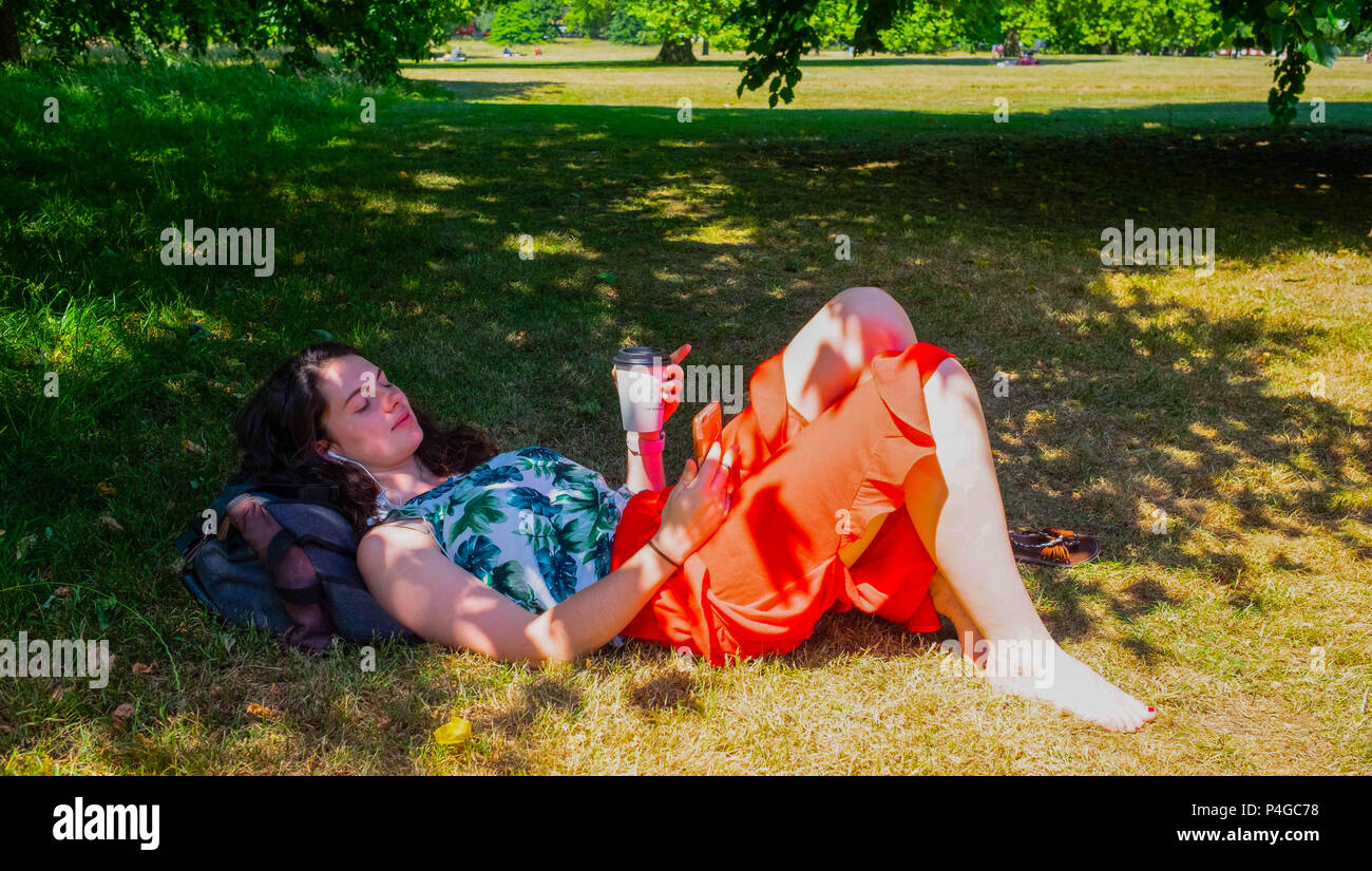 Londra, Inghilterra. Il 22 giugno 2018. Louise Craker, 22, trova qualche ombra dove si può ascoltare la sua musica e bere il caffè,in Hyde Park in un posto molto soleggiato giorno a Londra. Questo tempo soleggiato è detto di continuare per i prossimi giorni. ©Tim anello/Alamy Live News Foto Stock