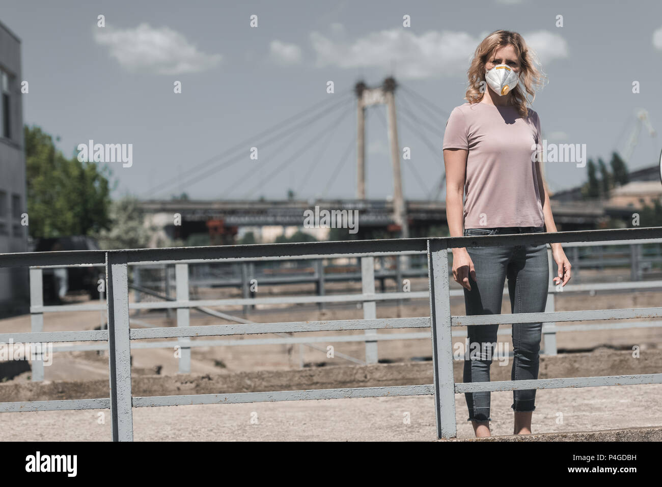 Donna in maschera protettiva in piedi sul ponte, l'inquinamento atmosferico concetto Foto Stock