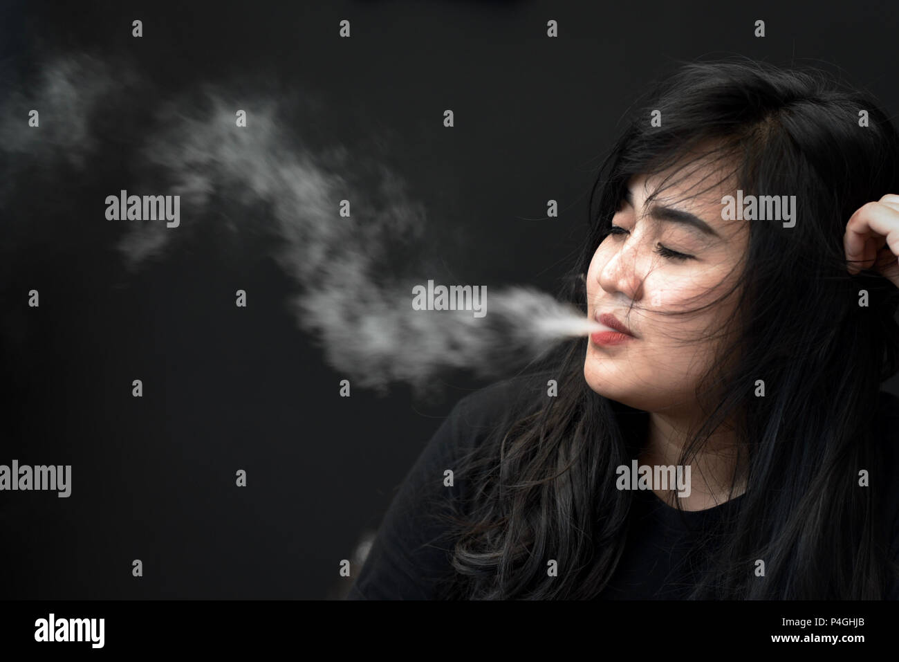 Una donna che posano per una foto mentre vaping durante una sigaretta elettronica fiera di Jakarta, Indonesia. Foto Stock