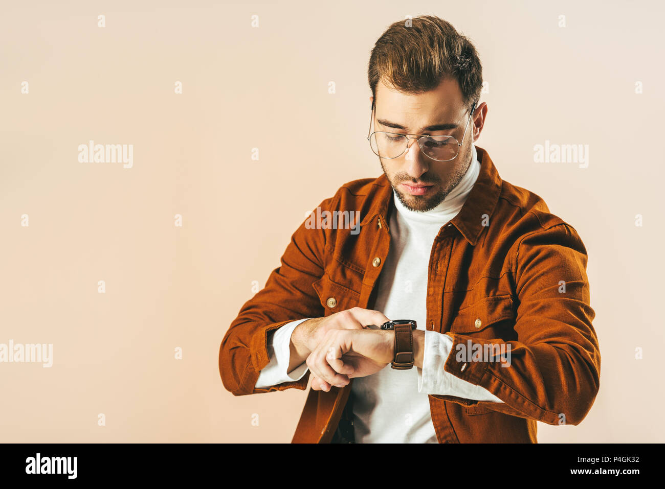 Ritratto di uomo bello controllando il tempo di guardia isolati su beige Foto Stock