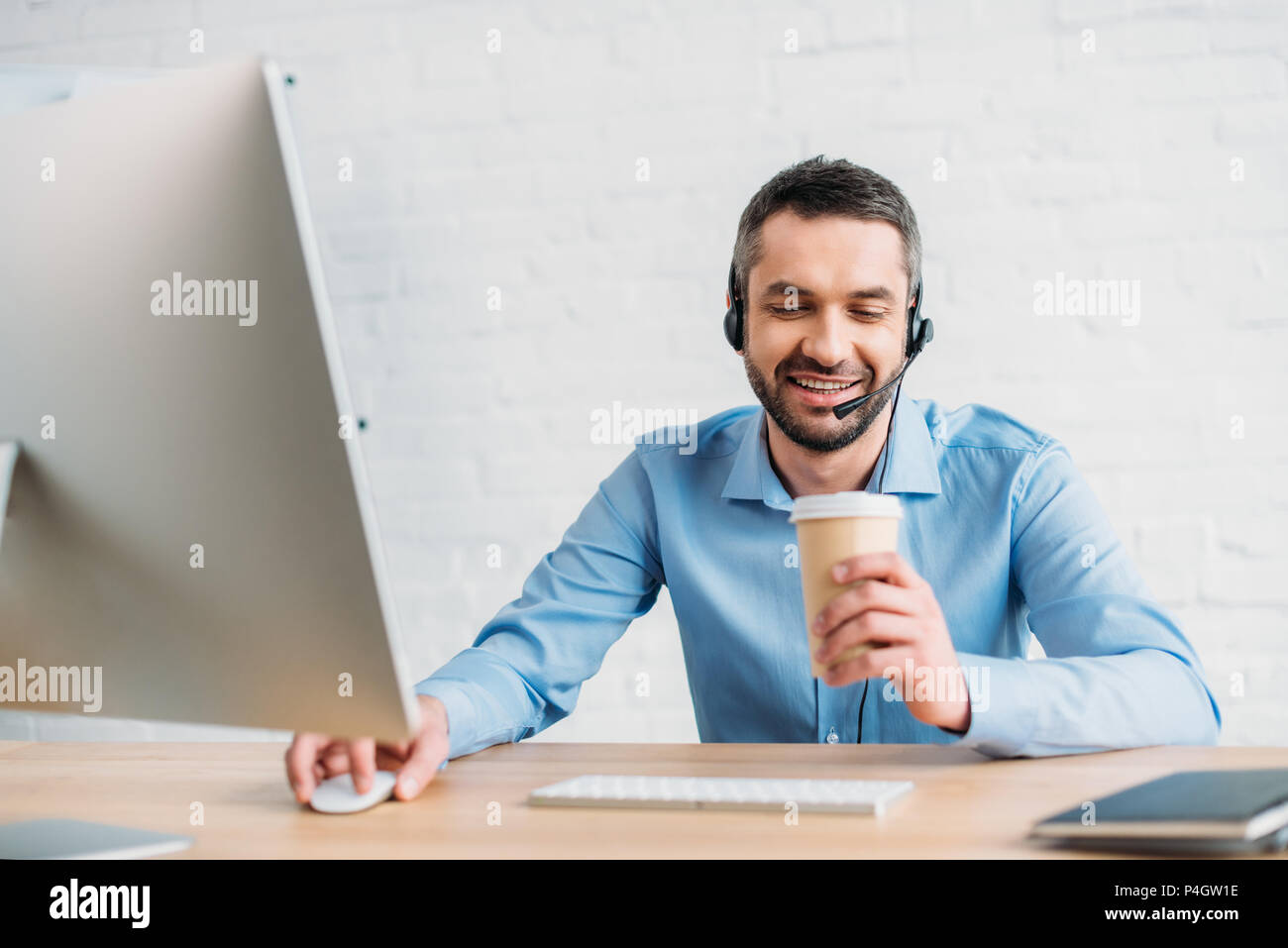 Adulto felice il supporto tecnico professionale di lavoro in ufficio e di bere il caffè dal bicchiere di carta Foto Stock