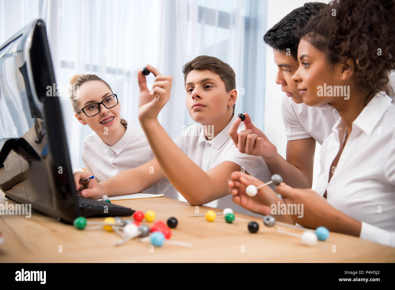 Giovani studenti multiculturale di prelievo modello molecolare per la lezione di scienze Foto Stock