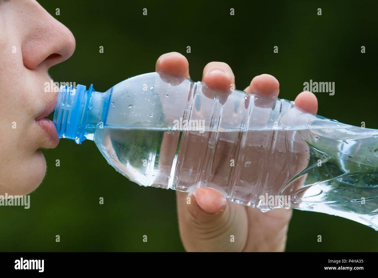 Donna di bere acqua da una bottiglia su sfondo natura Foto Stock