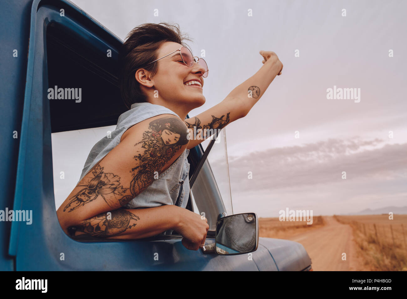 Colpo di attraente giovane donna godendo di viaggio su un giorno d'estate. Felice giovane femmina alzando la mano al di fuori della finestra di auto. Foto Stock