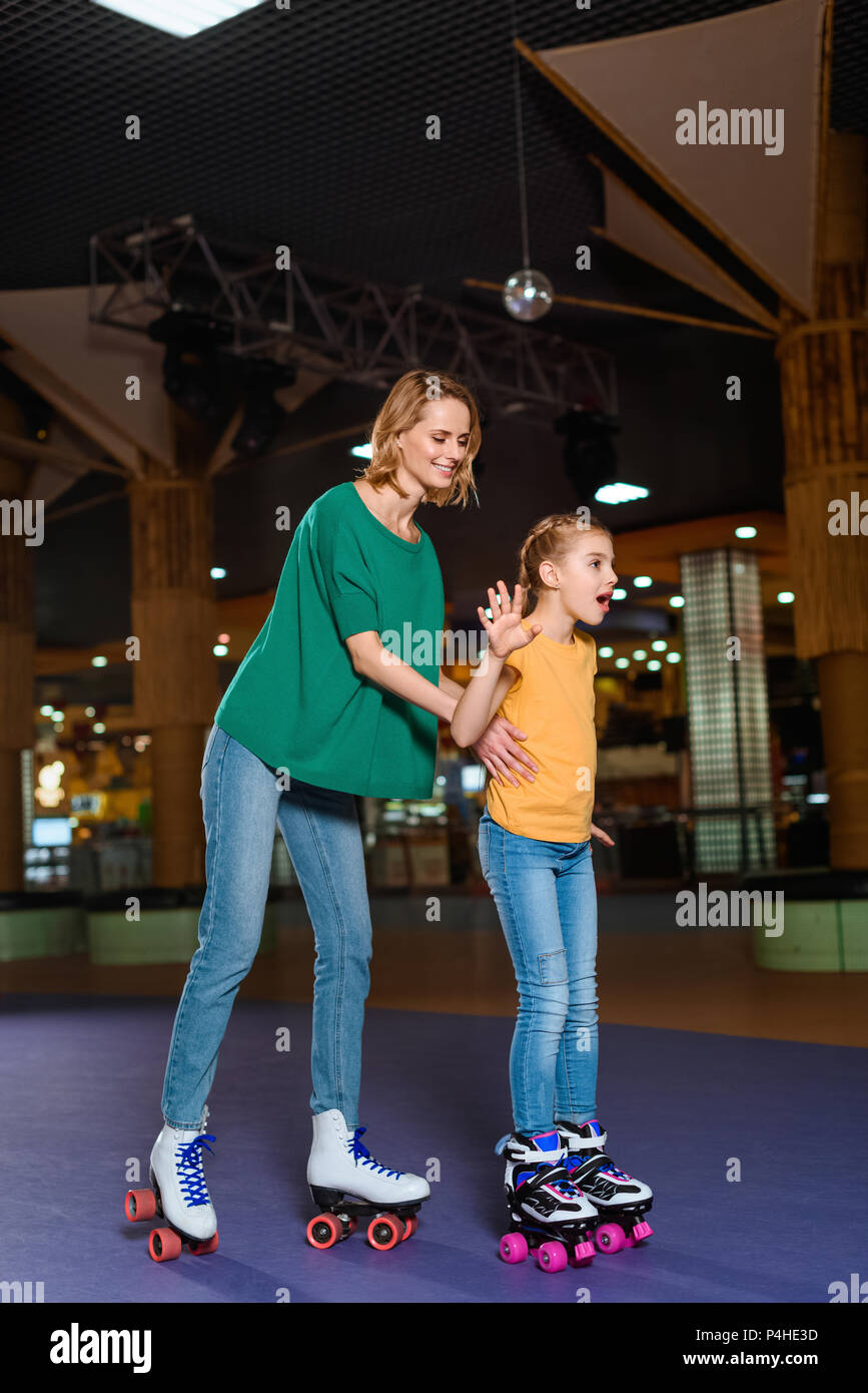 Sorridente madre e figlia insieme pattinare sulla pista di pattinaggio sul rullo Foto Stock