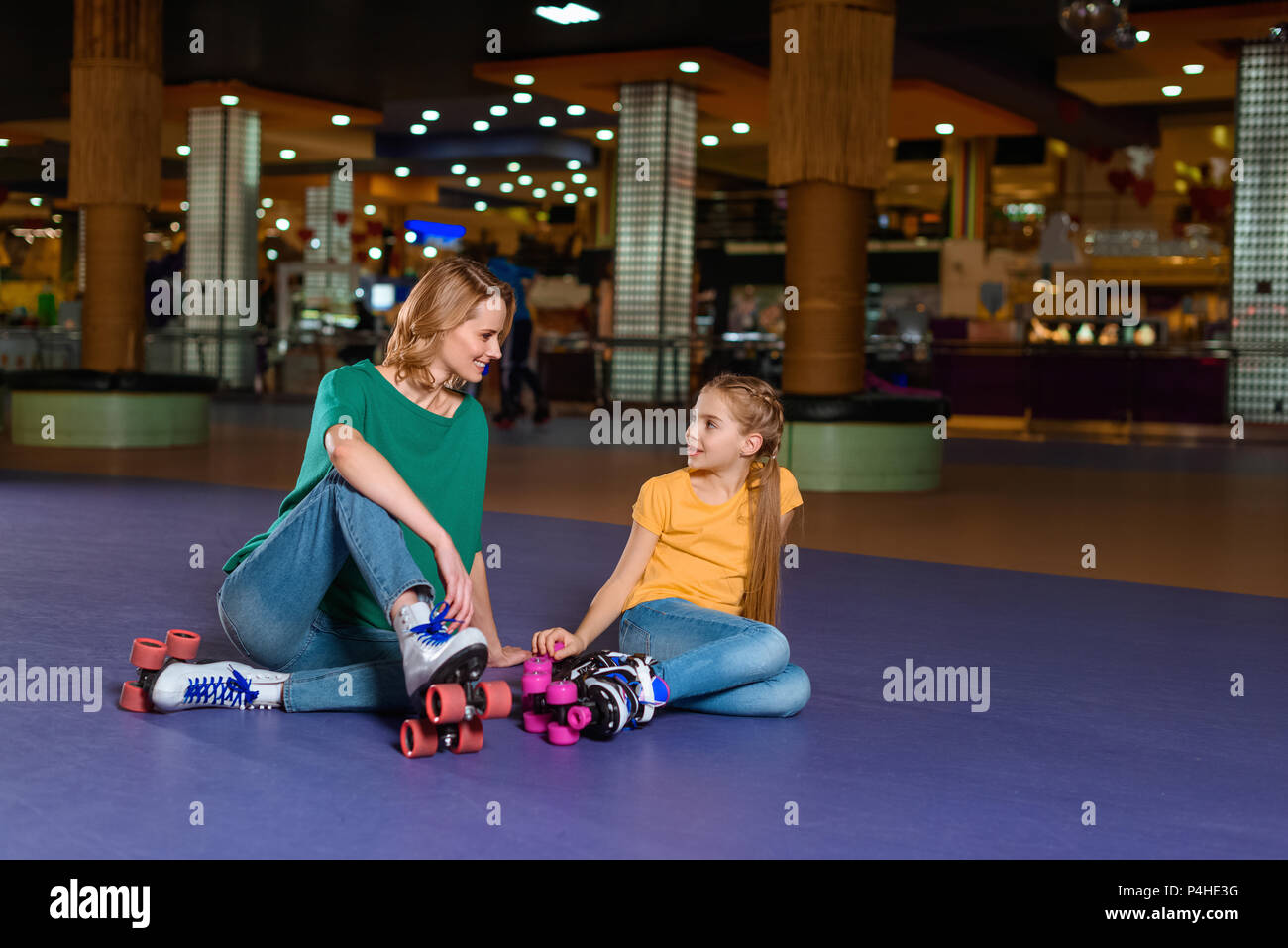 Madre e figlia piccola seduta sul rullo rink insieme Foto Stock
