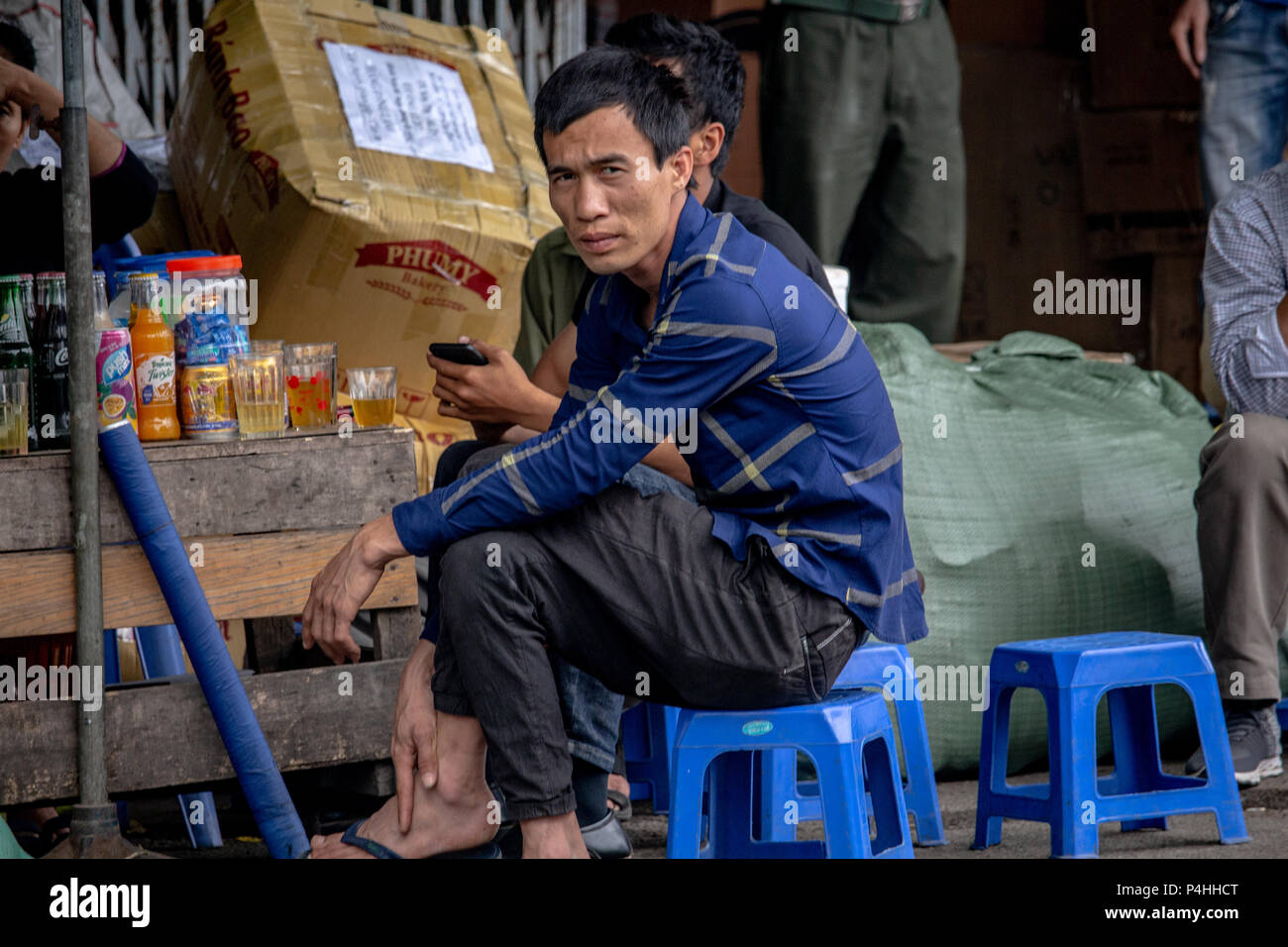 Hanoi, Vietnam - Marzo 16, 2018: uomo seduto su una sedia di plastica in una strada con bar e bere 'bia hoi', il locale di infuso di Hanoi di birra Foto Stock