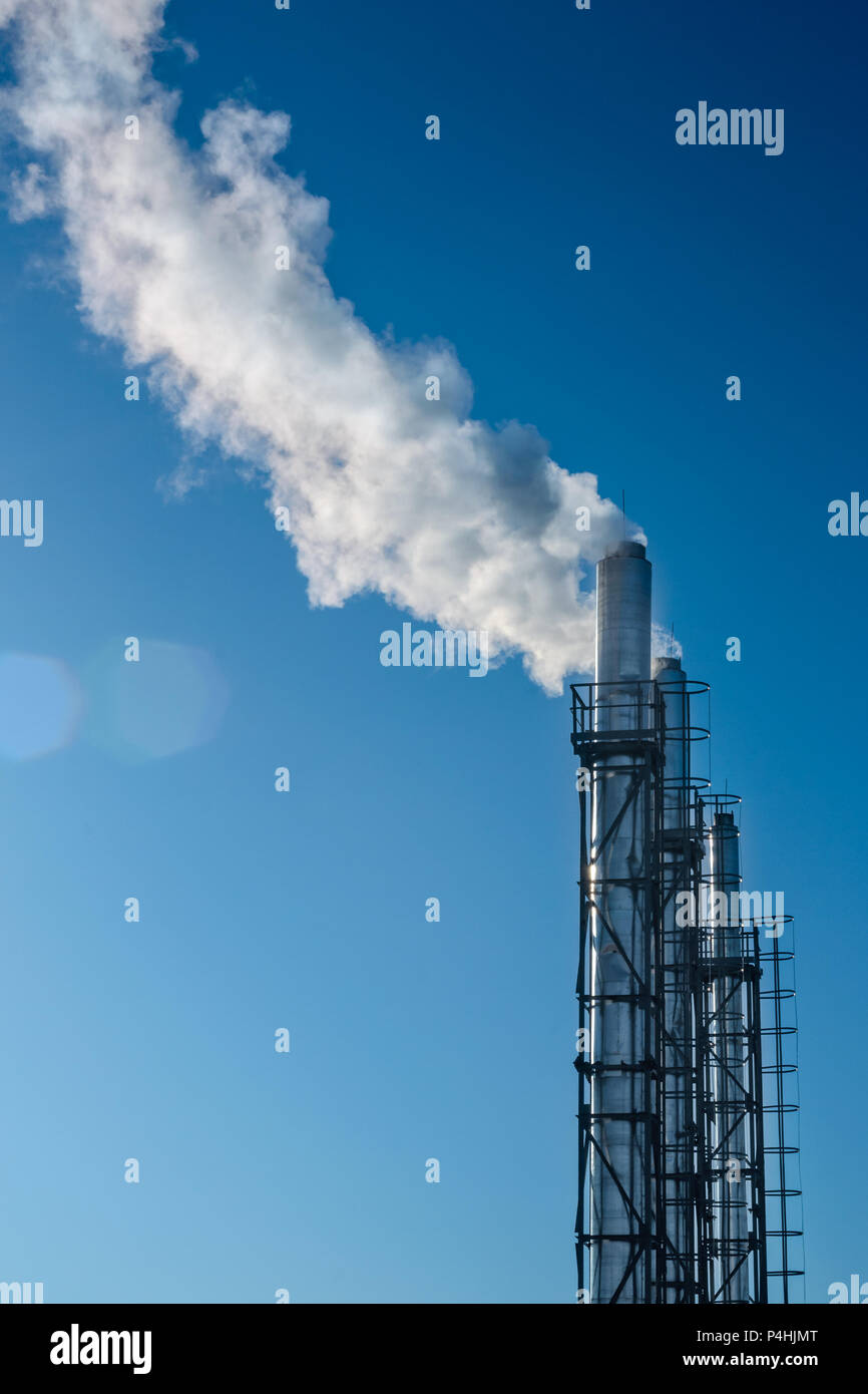 Tre tubi di fumo contro il cielo blu. Il concetto di inquinamento ambientale. Composizione verticale Foto Stock