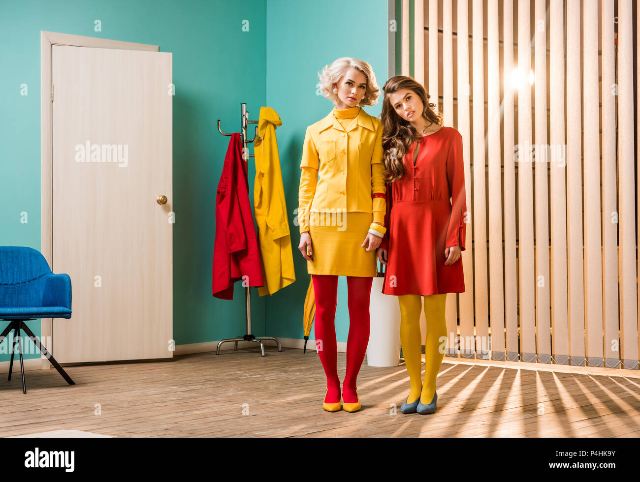 Giovani in stile retrò donne in piedi in camera colorata, casa di bambola concept Foto Stock
