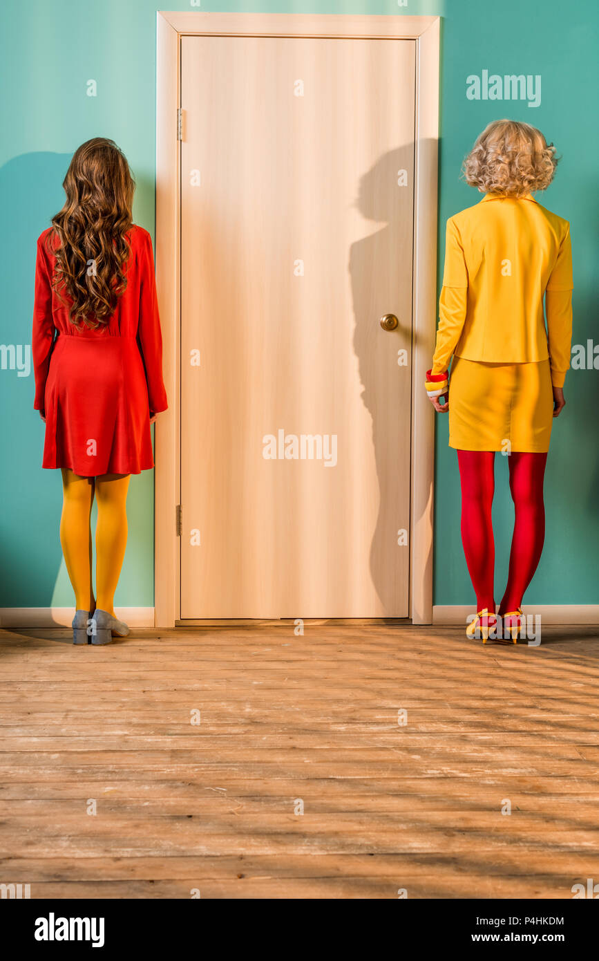 Vista posteriore di stile retrò donne in piedi presso la porta a colorato appartamento, casa di bambola concept Foto Stock