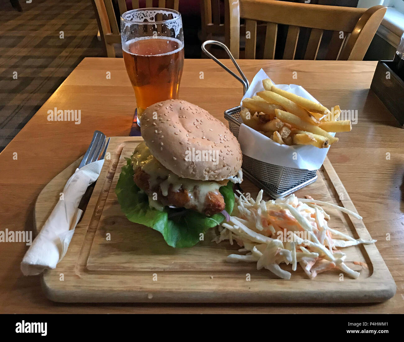 Hamburger di pollo pasto con patatine fritte, coleslaw e una pinta di birra in un pub tradizionale inglese, Somerset, South West England, Regno Unito Foto Stock