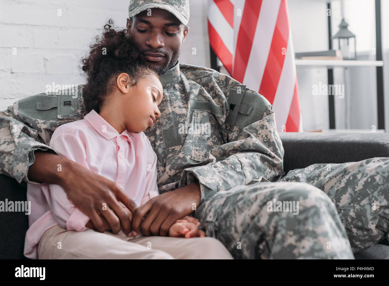 Padre in uniforme militare e americano africano bambino abbracciando a casa Foto Stock