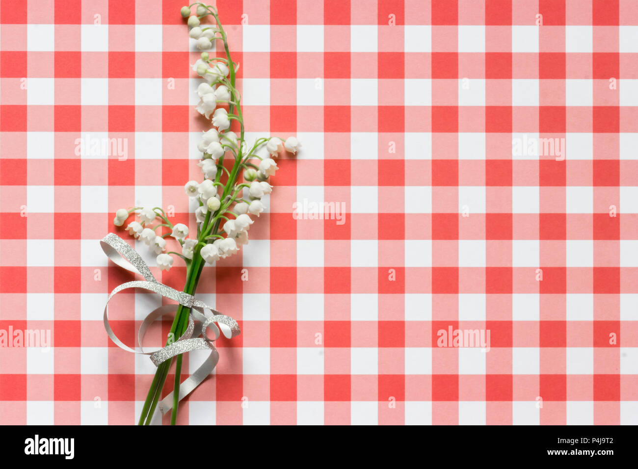 Lilly della valle sul rosso e bianco a scacchi sfondo pattern Foto Stock