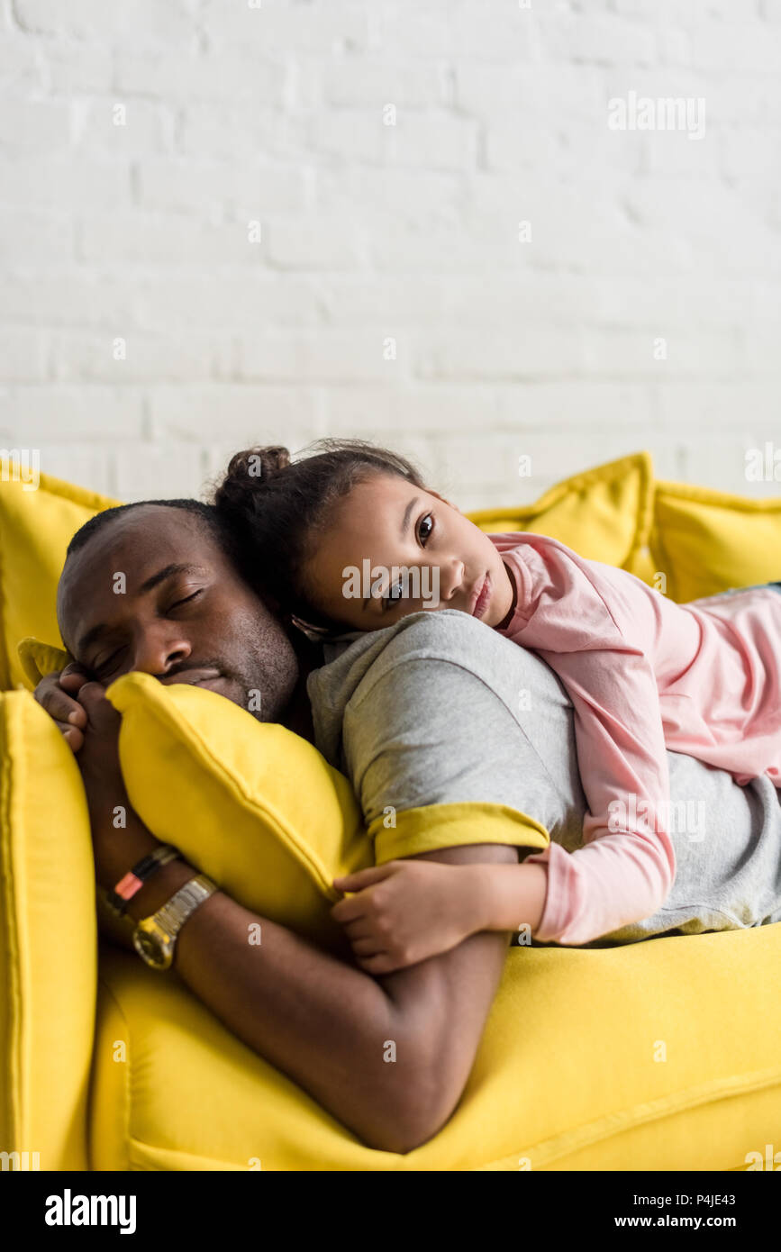 Figlia giacente sul retro del padre mentre egli dormiva sul lettino Foto Stock