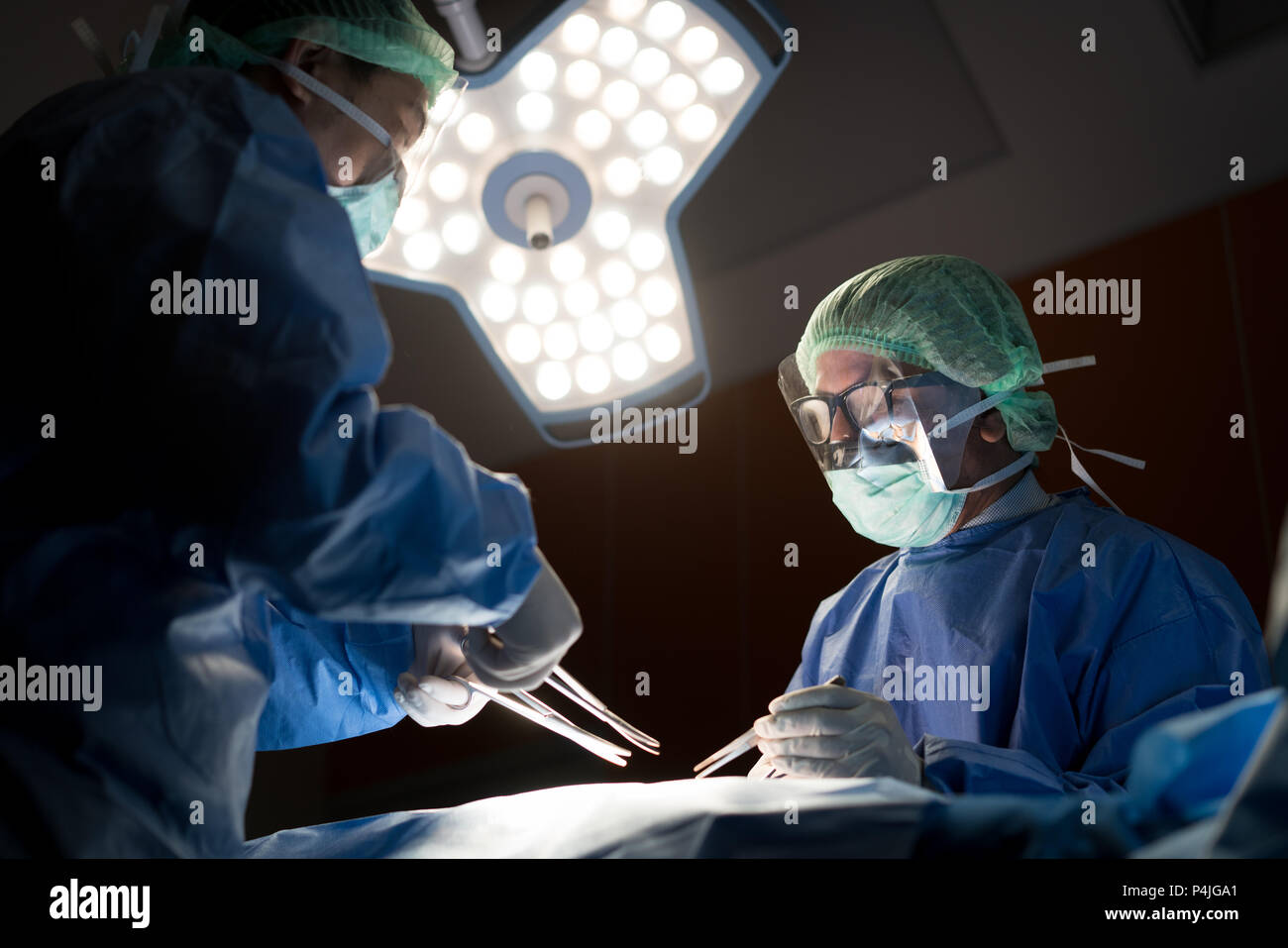 Asian medico e un assistente in sala operatoria per chirurgia vascolare venosa clinica di chirurgia in ospedale. Foto Stock