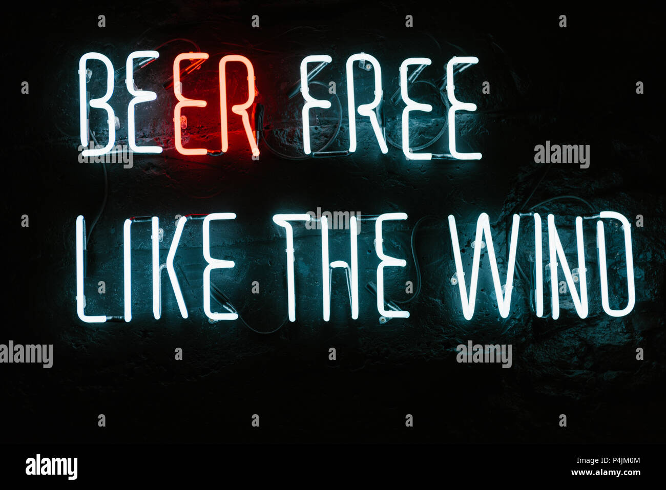 La birra libera come il vento neon iscrizione sulla parete scura in bar Foto Stock