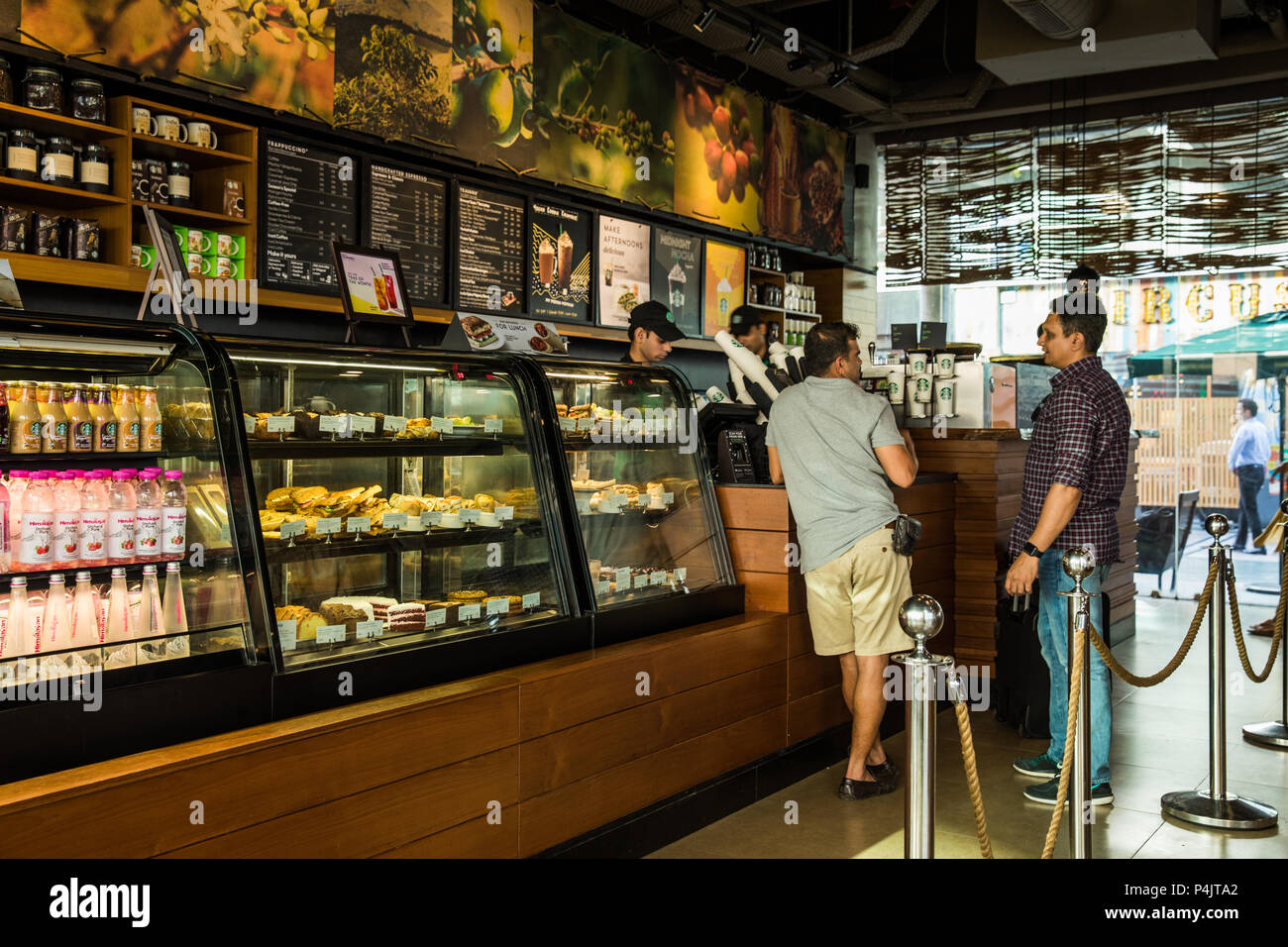 La mezza età uomini conversando presso Starbucks contatore, Gurugram, India Foto Stock
