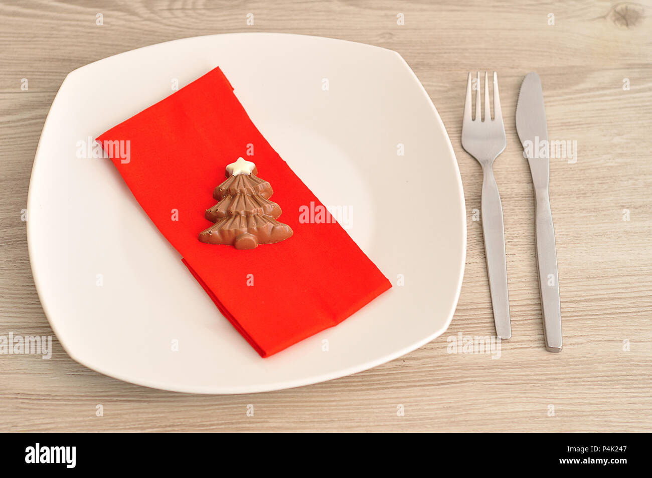 Una semplice impostazione del luogo per il Natale costituito da una piastra, forcella, coltello, rosso igienico e una forma di cioccolato albero di natale Foto Stock