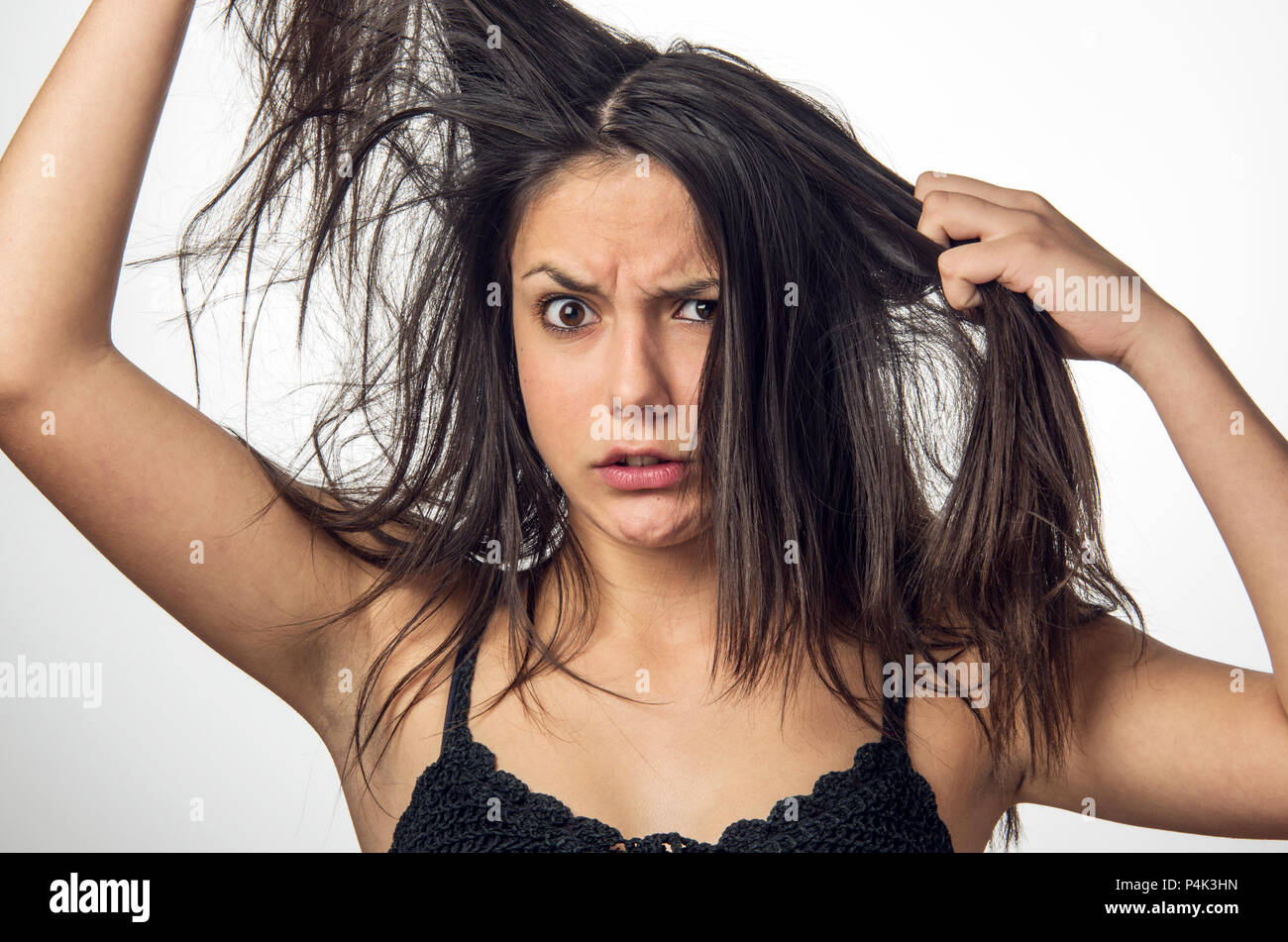 Bruna ragazza adolescente con rabbia expression tirando i suoi capelli sporchi Foto Stock